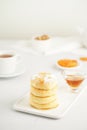 Fried cheese cakes, sweet cheese pancakes on white plate on white background, vertical. Home tea party