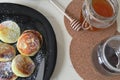 fried cheese pancakes in a black plate and nearby cans of honey and coffee