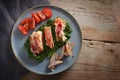 Fried  chicken breast fillet rolled in bacon on cream spinach with roasted onions and tomatoes on a blue plate and a rustic wooden Royalty Free Stock Photo