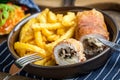 Fried chicken breast stuffed with mushrooms and cheese wrapped in ham served with fries and salad Royalty Free Stock Photo