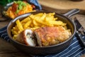 Fried chicken breast stuffed with mushrooms and cheese wrapped in ham served with fries and salad Royalty Free Stock Photo