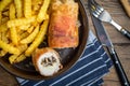 Fried chicken breast stuffed with mushrooms and cheese wrapped in ham served with fries and salad Royalty Free Stock Photo