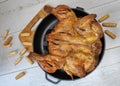 Fried chicken. On the table in a cast-iron pan, with a crisp, Golden crust. Bread sticks with sesame seeds. Wooden background