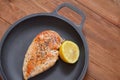 Fried chicken fillet is lying on a frying pan with a lemon