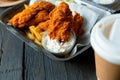 Fried chicken and french fries and in a takeaway container on the wooden background. Food delivery and fast food concept