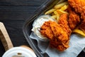 Fried chicken and french fries and in a takeaway container on the wooden background. Food delivery and fast food concept Royalty Free Stock Photo