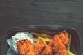 Fried chicken and french fries and in a takeaway container on the wooden background. Food delivery and fast food concept Royalty Free Stock Photo
