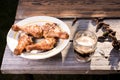 Fried chicken legs in a plate and a glass of beer on a wooden table/fried chicken legs with beer on a picnic on a sunny day
