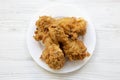 Fried chicken legs on a white plate over white wooden background, close-up. Top view Royalty Free Stock Photo
