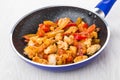 Fried chicken meat with sweet pepper in blue frying pan