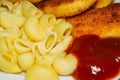 Fried chicken nuggets and boiled pasta with ketchup on a plate. Close up