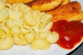 Fried chicken nuggets and boiled pasta with ketchup on a plate. Close up Royalty Free Stock Photo