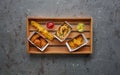 Fried chicken nuggets, legs, crispy octopus and spiral potato chips on wooden tray, top view, copy space. Street food