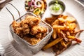 Fried chicken nuggets in metal basket served with french fries on a white plate Royalty Free Stock Photo