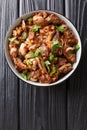 Fried chicken offal liver, heart and stomachs with onions, tomatoes and spices close-up in a bowl. vertical top view