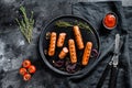 Fried chicken sausages with onion, garlic and rosemary. Black background. Top view