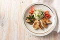 Fried chicken slices with cauliflower rice, mushroom ragout and tomatoes, on a light wooden table, healthy slimming with low carb