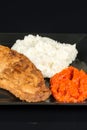 Fried chicken white meat with mashed potatoes and paprika ajvar on the black plate Royalty Free Stock Photo