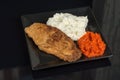 Fried chicken white meat with mashed potatoes and paprika ajvar on the black plate Royalty Free Stock Photo