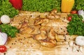 Fried chicken wings, baked chicken on a wooden board with cherry tomatoes, lettuce leaves, garlic, chilli pepper Royalty Free Stock Photo