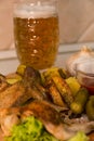 Fried chicken wings with baked potatoes, served on a wooden board with pickled gherkins, tomato sauce and fresh lettuce leaves. A Royalty Free Stock Photo