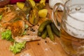 Fried chicken wings served on a wooden Board with spices, baked potatoes, pickled gherkins and fresh lettuce leaves. Royalty Free Stock Photo