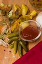 Fried chicken wings with spicy and baked potatoes, served on a wooden board with pickled gherkins, tomato sauce and fresh lettuce Royalty Free Stock Photo