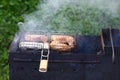 Fried chiken pieces on the grill with burning wood. Hot tasty smokey barbecue meal at coals and burnt firewood. Cooking on fire ou Royalty Free Stock Photo