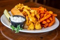 Fried clams with sweet potato fries, pickle and cole slaw on table