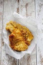 Fried coalfish on waxed paper, wooedn background