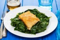 Fried cod fish with greens on white plate on blue background Royalty Free Stock Photo