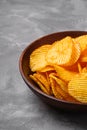 Fried corrugated golden potato chips in brown wooden bowl on concrete background Royalty Free Stock Photo