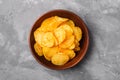 Fried corrugated golden potato chips in brown wooden bowl on concrete background Royalty Free Stock Photo