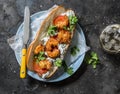 Fried crispy tempura shrimp, tomato and tzadziki sauce sandwich on dark background, top view