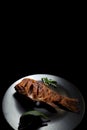 Fried crucian carp fish on a plate, on a black background