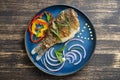 Fried crucian carp with pepper and onion on a plate on a wooden background. Top view