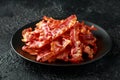 Fried crunchy Streaky Bacon pieces in a black plate Royalty Free Stock Photo
