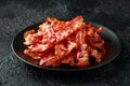 Fried crunchy Streaky Bacon pieces in a black plate