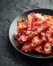Fried crunchy Streaky Bacon pieces in a black plate Royalty Free Stock Photo