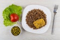 Fried cutlet, buckwheat in plate, tomato, green peas, fork Royalty Free Stock Photo