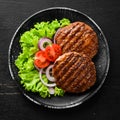 fried cutlet for burger with vegetables. In a black plate on a wooden background Top view. Royalty Free Stock Photo