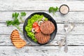 fried cutlet for burger with vegetables. In a black plate on a wooden background Top view. Royalty Free Stock Photo