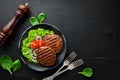 fried cutlet for burger with vegetables. In a black plate on a wooden background Top view. Royalty Free Stock Photo