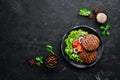 fried cutlet for burger with vegetables. In a black plate on a wooden background Top view. Royalty Free Stock Photo