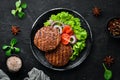 fried cutlet for burger with vegetables. In a black plate on a wooden background Top view. Royalty Free Stock Photo