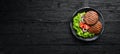 fried cutlet for burger with vegetables. In a black plate on a wooden background Top view. Royalty Free Stock Photo