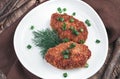 Fried cutlets with herbs in a white ceramic plate on a brown wooden background. Royalty Free Stock Photo