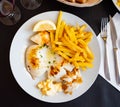 fried cuttlefish drizzled with white garlic and parsley sauce,lemon wedge and french fries on plate