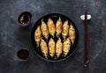 Fried dumplings Gyoza in pan, soy sauce, chopsticks on dark stone background Royalty Free Stock Photo