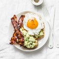 Fried egg, bacon and avocado sandwiches on light background, top view. Delicious breakfast